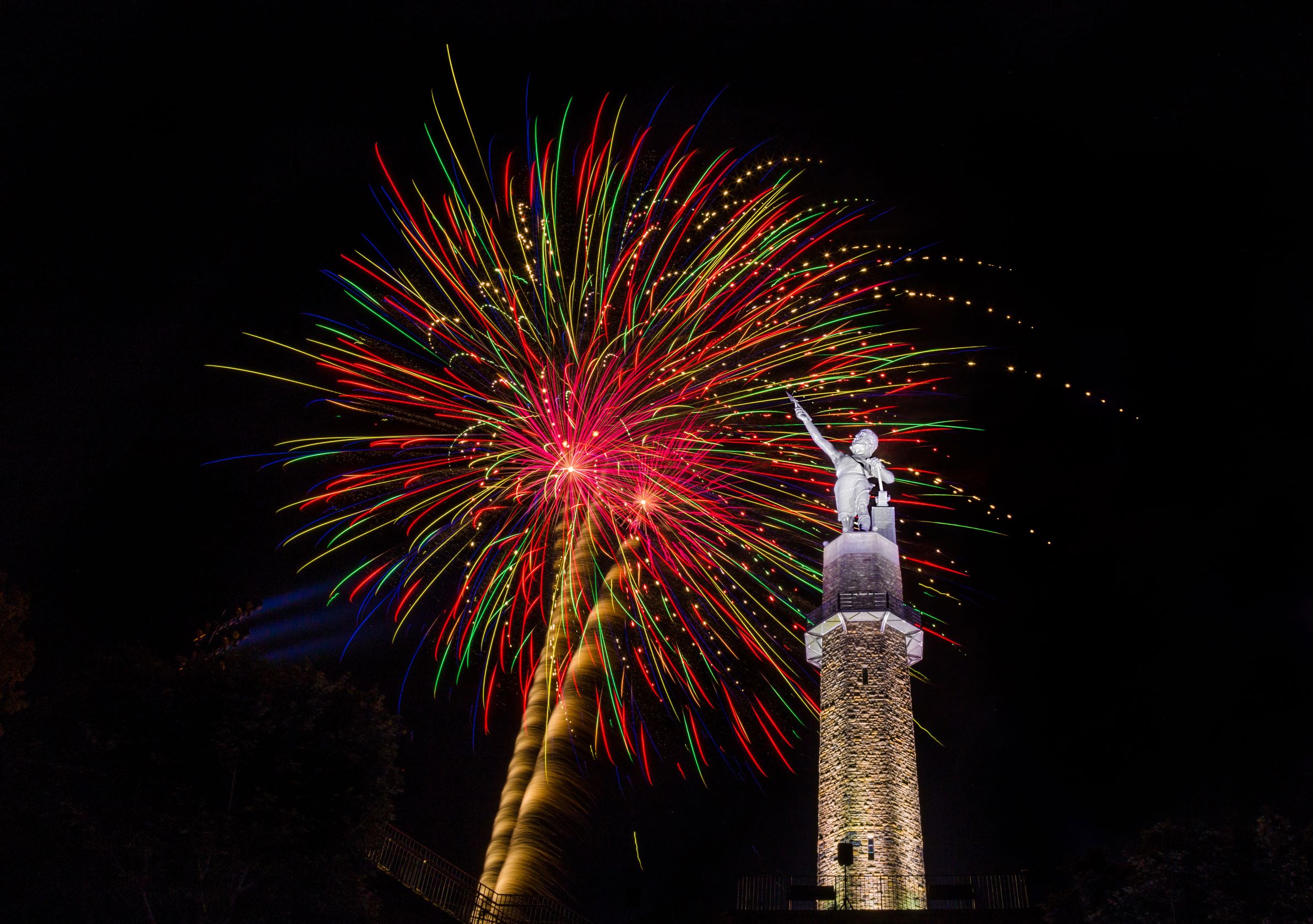 Red, pink, green, and blue fireworks over the statue of Vulcan 